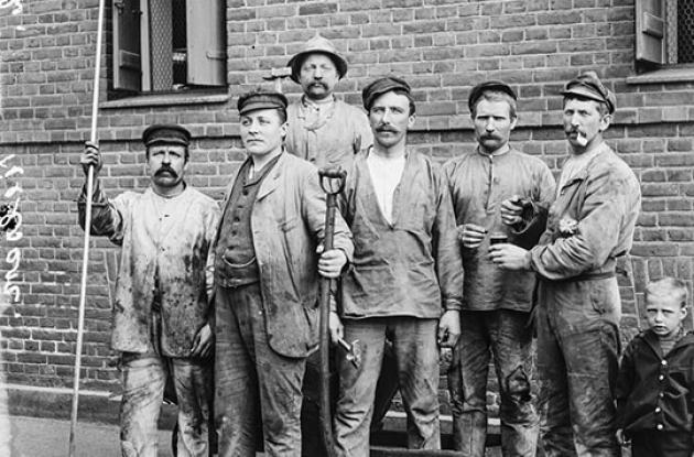 Gruppe af mandlige arbejdere står med forskellige redskaber