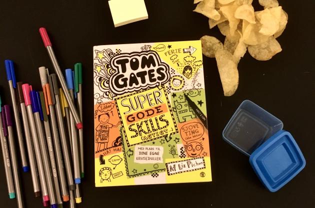 Bogen Tom Gates omringet af chips, en bil og tuscher