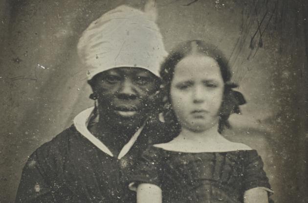 Foto af lille hvid pige, der sidder med en sort kvinde