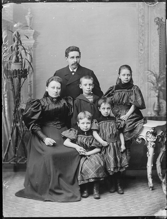 Familie på seks mennesker poserer i fint tøj