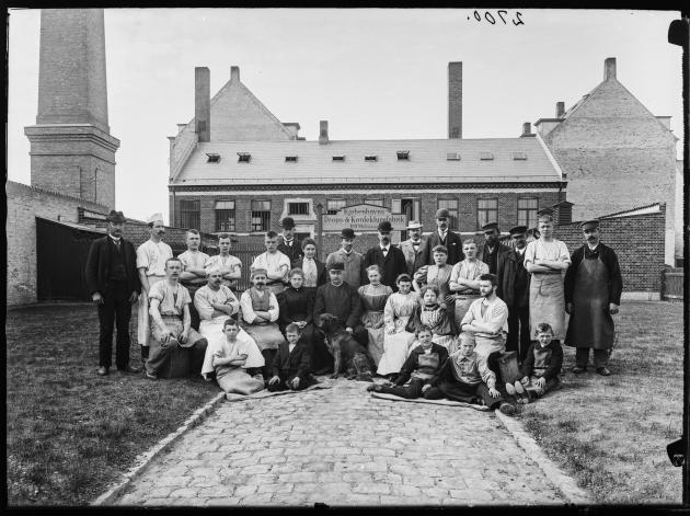Mænd og kvinder poserer i en gruppe foran en københavnsk fabrik