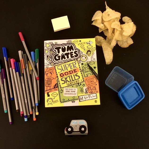 Bogen Tom Gates omringet af chips, en bil og tuscher