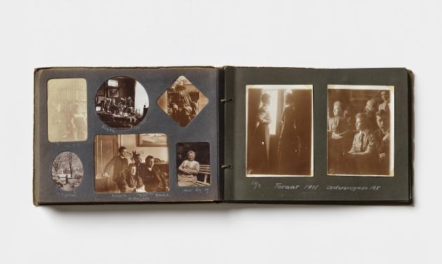 Et fotoalbum ligger åbent med to sider dækket af gamle familiebilleder